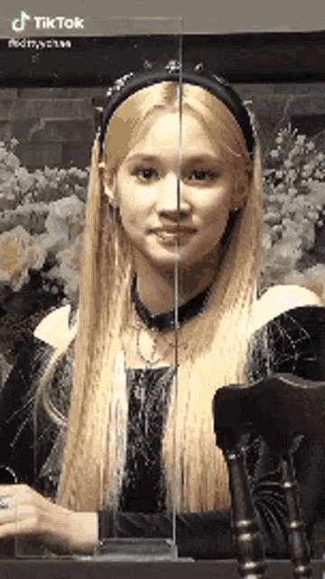 a woman with long blonde hair and a black headband is sitting in front of a chair .