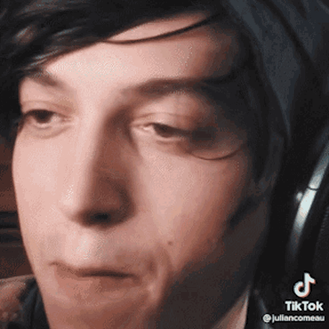 a close up of a person 's face with headphones on and a tiktok watermark .