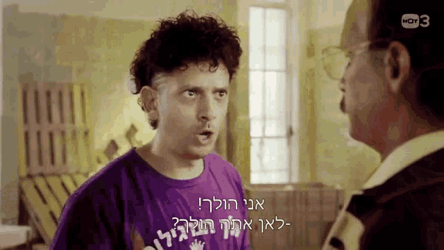a man in a purple shirt is talking to another man in a room