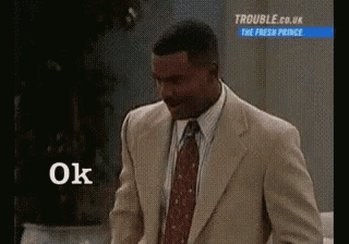 a man in a suit and tie is standing next to a sign that says `` ok '' .