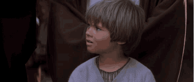 a young boy with blonde hair and blue eyes is looking at the camera