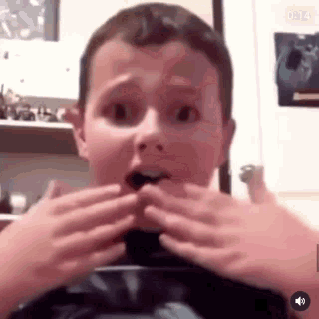 a young boy is making a funny face with his hands .