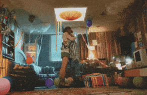 a woman is hugging another woman in a room with balloons and a ceiling light