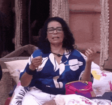 a woman wearing glasses is sitting on a bed with a purse