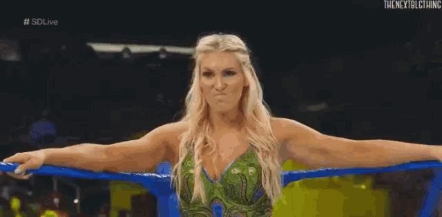a female wrestler is standing in a wrestling ring with her arms outstretched .