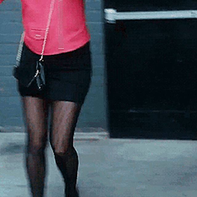 a woman in a red jacket and black skirt is walking