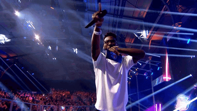 a man singing into a microphone in front of a crowd with a sign that says ' x ' on it