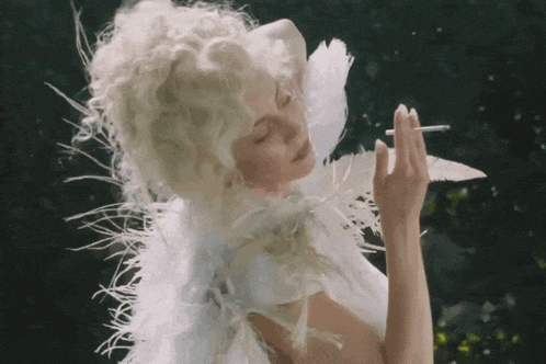a woman dressed as an angel with feathers on her wings is smoking a cigarette