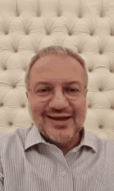 a man wearing glasses and a striped shirt is smiling