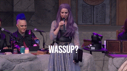 a woman with purple hair is speaking into a microphone and the word wassup is on the screen