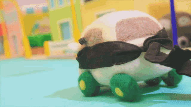 a stuffed animal with green wheels and a black scarf on it