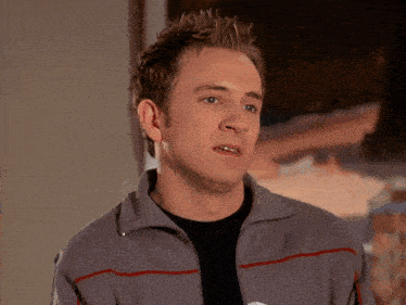 a man wearing a grey jacket with red stripes