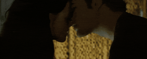 a man and woman are kissing in a dark room .