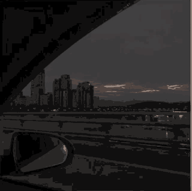 a car driving down a highway at night with a city in the background