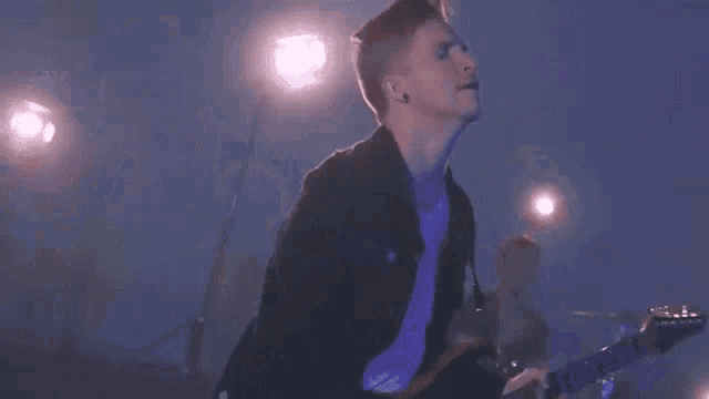 a young man is playing a guitar on a stage .