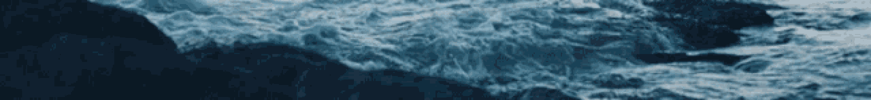 a close up of a body of water with waves crashing against a rock