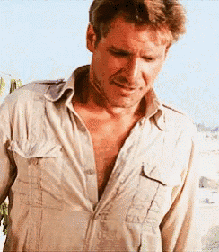 a man in a tan shirt is standing on a beach .