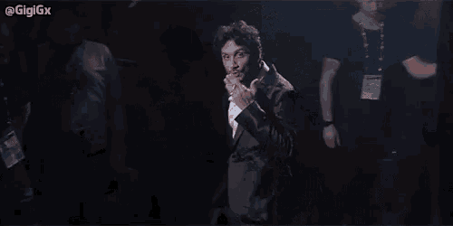 a man in a suit is making a funny face while standing on a stage .