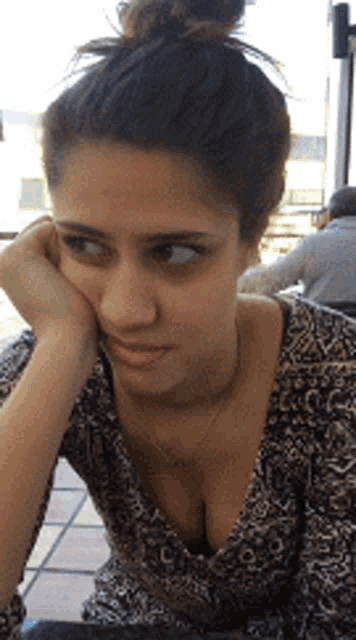 a woman with her head resting on her hand is looking at the camera