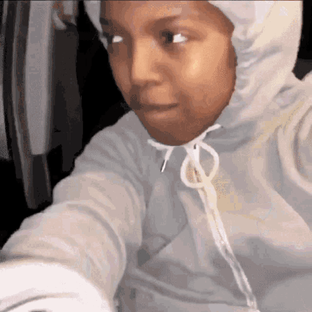 a woman wearing a hooded jacket is taking a selfie