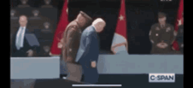 a blurry picture of two men standing next to each other in front of a crowd .