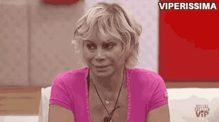 a woman in a pink shirt is sitting on a couch and smiling .