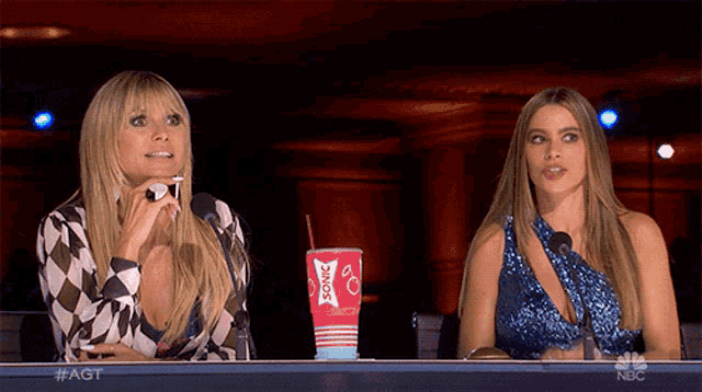 two women sit at a table with a cup that says sonic