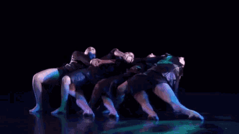 a group of people are dancing in a dark room with blue lights