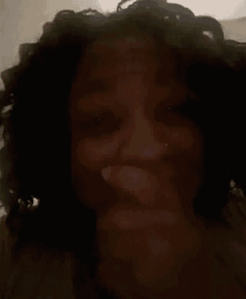 a woman with curly hair covering her face with her hand