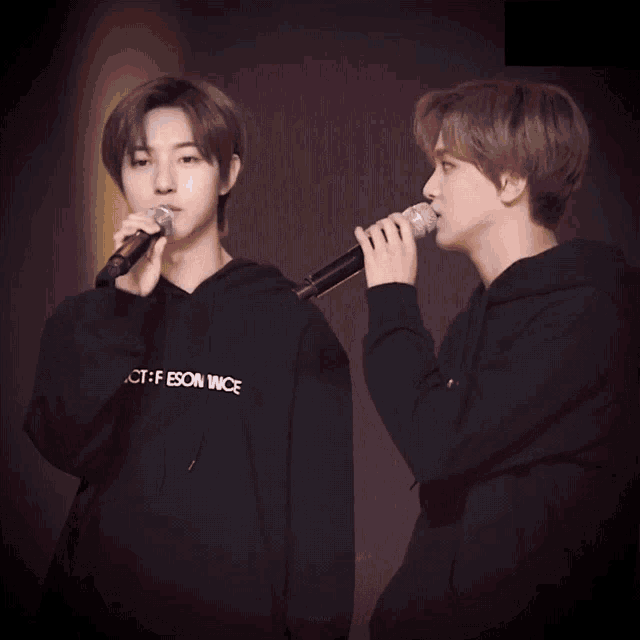 a man singing into a microphone next to another man wearing a black hoodie that says ct-f eson wice