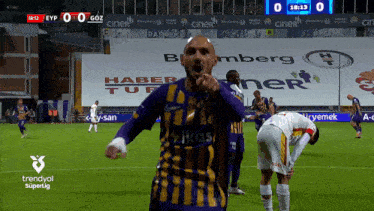 a soccer player wearing a purple and yellow jersey with ikas on it