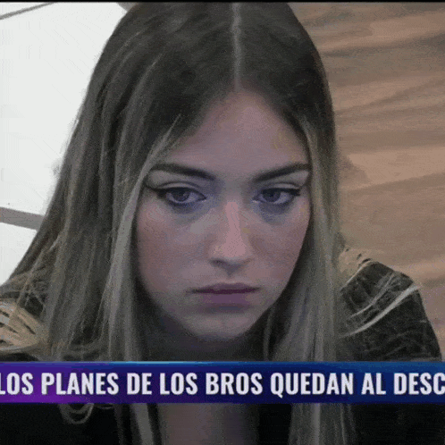 a woman sitting in front of a sign that says " los planes de los bros quedan al desc "