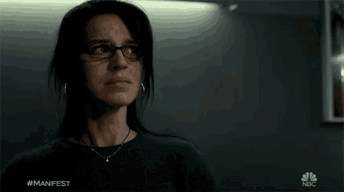 a woman wearing glasses and a necklace with the hashtag #manifest