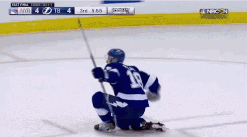 a hockey player is kneeling down on the ice and holding a stick