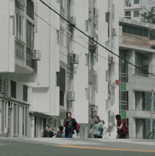 a group of people walking down a street in front of a building with a red sign that says ' a ' on it
