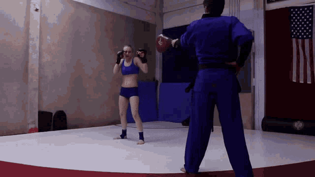 a woman in a blue top and shorts is practicing martial arts with a man in a blue uniform