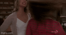 two women are standing next to each other with their arms in the air and laughing .