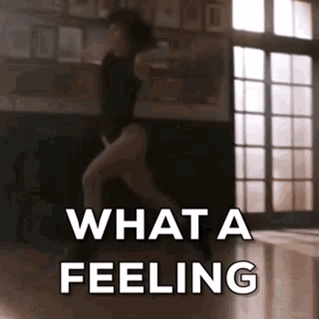 a woman is dancing in a room with the words `` what a feeling '' written on the floor .