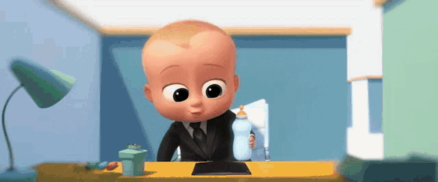 a baby in a suit and tie is sitting at a desk holding a bottle and a piece of paper