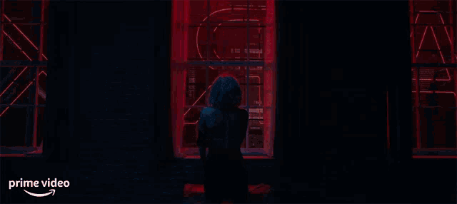 a woman is standing in front of a window with a prime video logo on the bottom