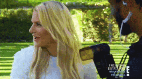 a woman with long blonde hair is sitting in a park talking to a man .