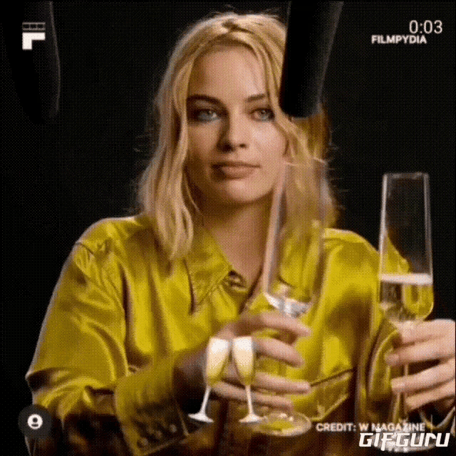 a woman in a yellow shirt is holding two champagne glasses .