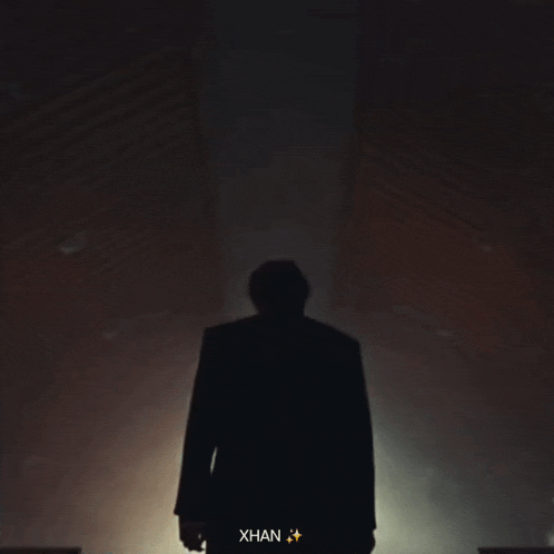 a man in a trench coat is walking down a dark hallway with the name xhan on the bottom right