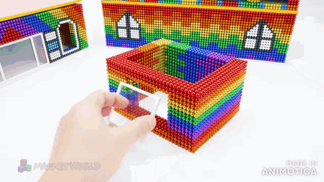 a person is holding a rainbow house made of magnets with the words made in animatica on the bottom