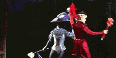 a man in a tuxedo is dancing with two women on a stage