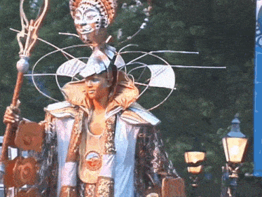a man in a costume holds a cane in front of a sign that has the letter o on it