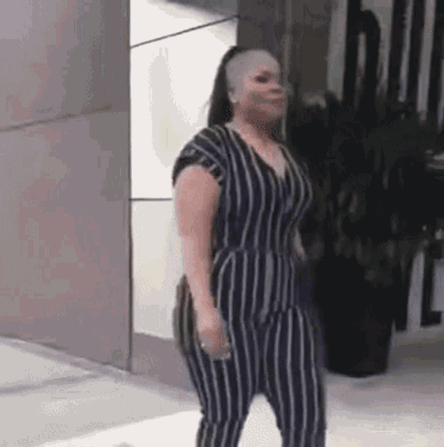 a woman in a black and white striped jumpsuit is walking down the street .