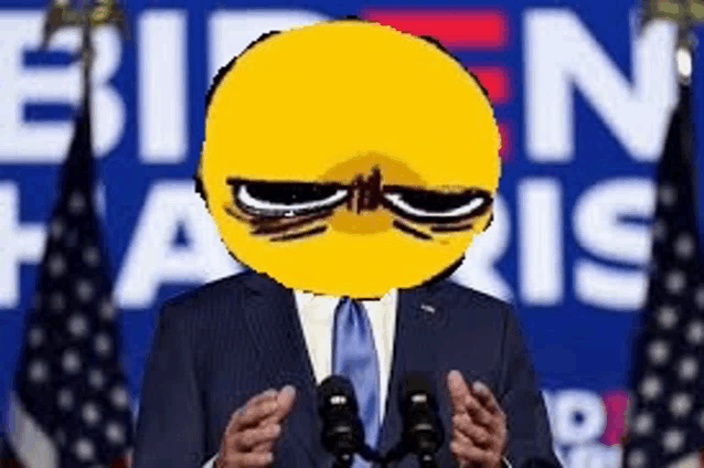a man in a suit and tie is giving a speech with a smiley face in front of him .