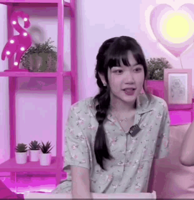 a girl is sitting on a couch in a room with a pink flamingo lamp .