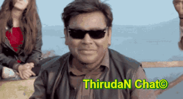 a man wearing sunglasses is smiling in front of a sign that says thiruda chat